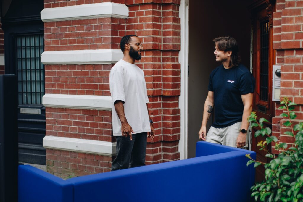 Twee mannen bij de voordeur tijdens het ophalen van een bank, verzorgd door een Brenger-koerier.