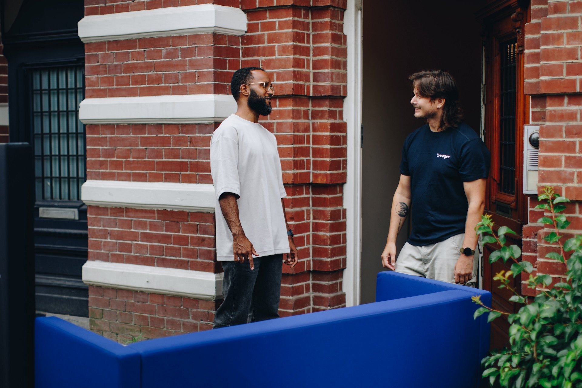 Twee mannen bij de voordeur tijdens het ophalen van een bank, verzorgd door een Brenger-koerier.